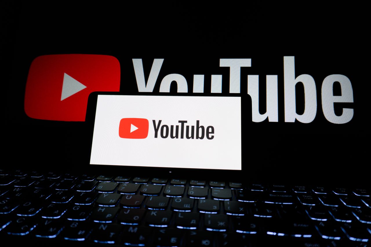 Gros plan du logo YouTube affiché sur l’écran d’un ordinateur portable dans un environnement sombre.